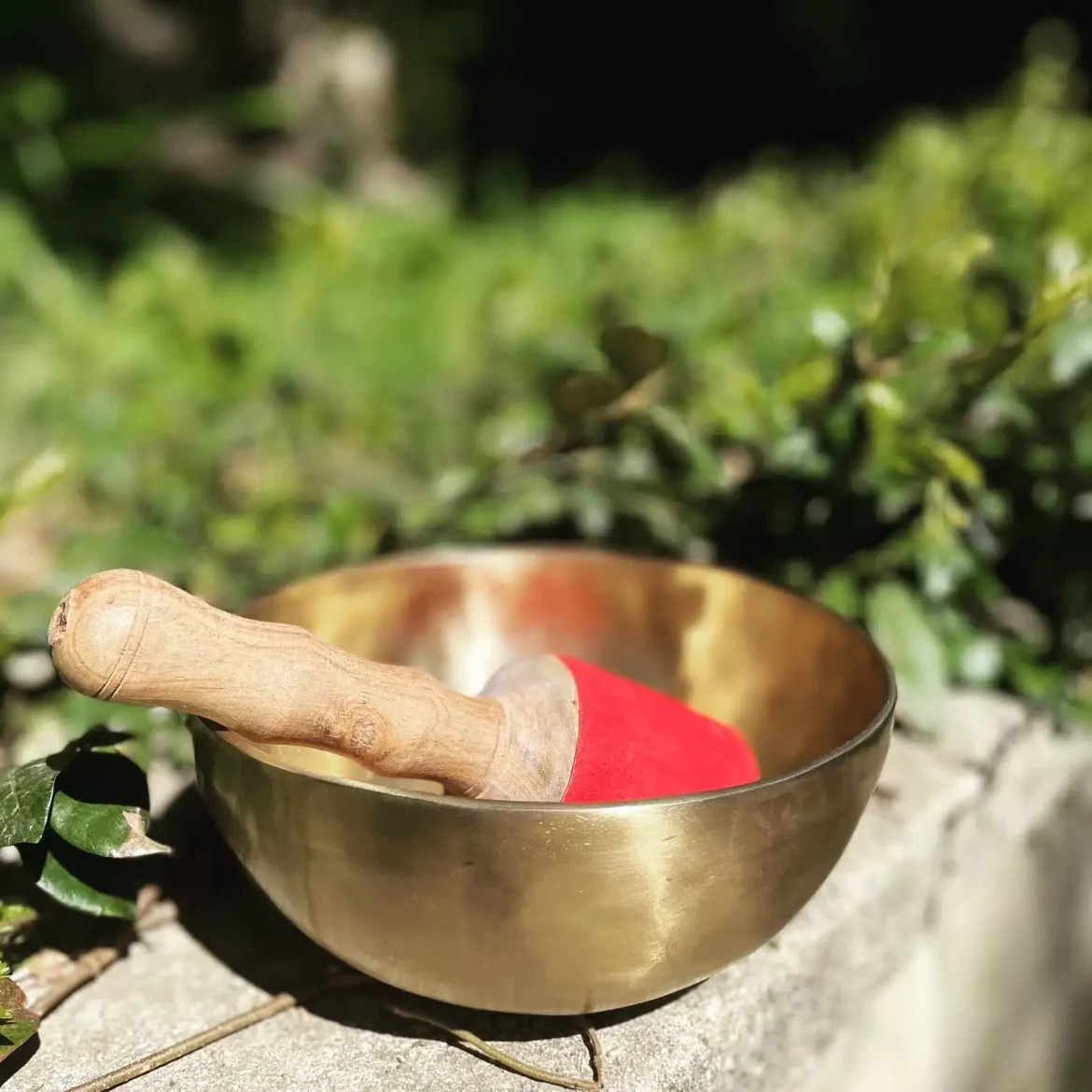 Bol tibétain posé au soleil avec une mailloche rouge en extérieur