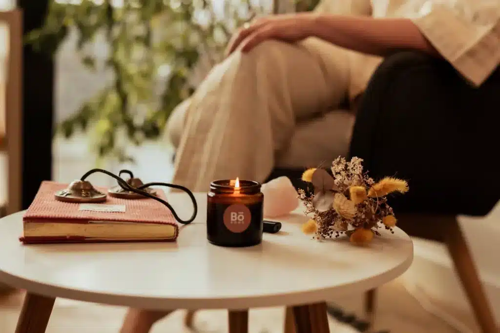 Scène d'intérieur apaisante avec une bougie Bo-DONG allumée, des tingshas et des fleurs séchées, symbolisant un rituel quotidien de bien-être.