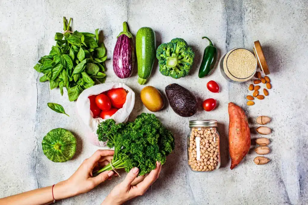 Composition d'aliments vivants et sains (légumes frais, pois chiches, noix) sur une table, illustrant une alimentation à haute vibration énergétique.