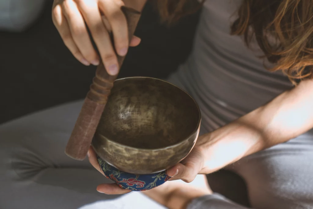 Femme tenant un bol tibétain au réveil, dans une ambiance douce et lumineuse