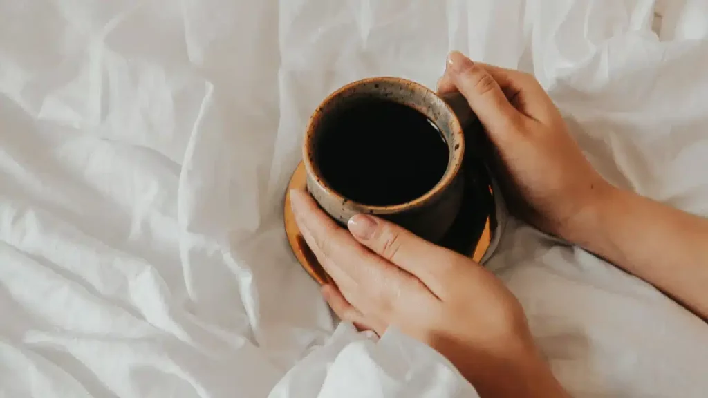 Mains tenant une tasse dans une lumière douce, illustrant le rituel intérieur et la sérénité quotidienne Bo-DONG.