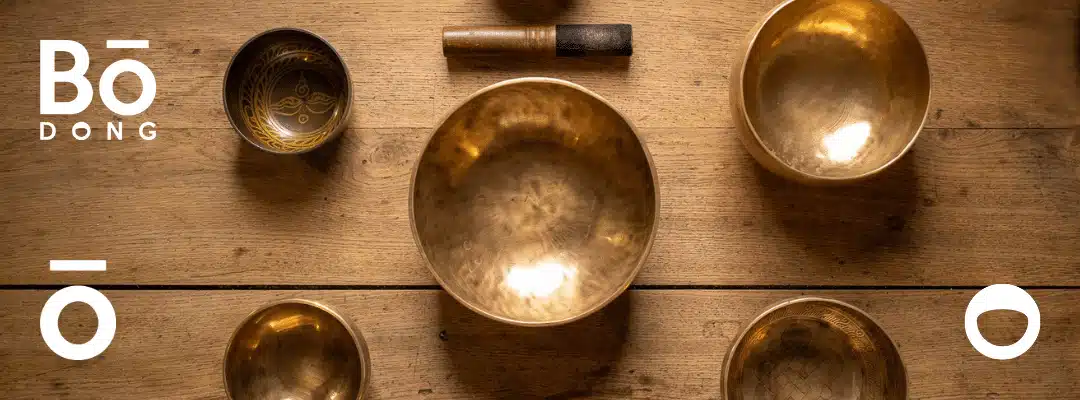Bols tibétains alignés sur une table en bois, utilisés en sonothérapie pour l’harmonisation des chakras.